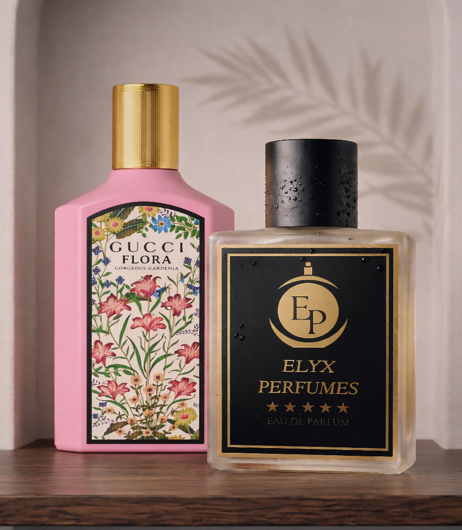 Two perfume bottles, one pink with floral design and gold cap, the other clear with black cap and 'Elyx Perfumes' label, on a wooden surface.